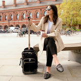 Aerolite 40x20x25cm Ryanair Maximum Eco-Friendly Premium Backpack Trolley Bag with 2 wheels and extendable handle, shown outdoors with a stylish woman seated on a bench.